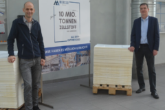 André Listemann, Managing Director Mercer Stendal, stands with team member and pulp sheet stacks to commemorate 10 million tonnes of production