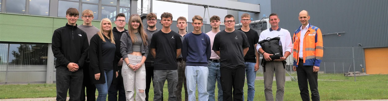 A group of young people stands in front of the Mercer Stendal pulp mill.