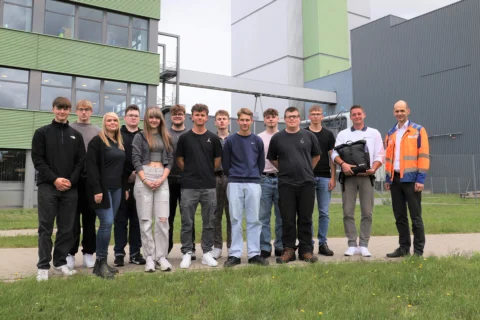 A group of young people stands in front of the Mercer Stendal pulp mill.