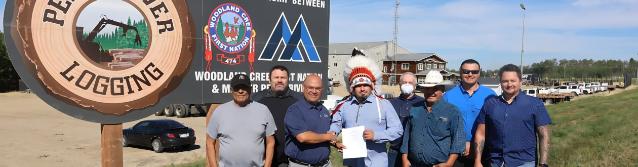 Employees of Mercer and Woodland Cree First Nation stand in front of a large Peace River Logging sign, holding a contract together.