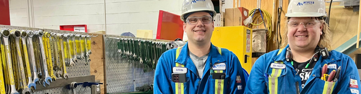 Levis Fortin and Dustin Thompson stand smiling in front of a tool bench. Dustin Thompson, Maintenance Technician, supported through electrical and instrumentation trade tickets.